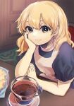  1girl black_shirt blonde_hair cup elbows_on_table green_eyes hand_on_own_arm hand_on_own_face highres kirisame_marisa looking_at_viewer rai_(3stone) shirt sitting solo table tea teacup touhou wooden_table 