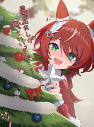  1girl absurdres animal_ears blush capelet christmas christmas_ornaments christmas_tree commentary_request dress ear_covers ear_ornament feather_hair_ornament feathers fur-trimmed_capelet fur_trim green_eyes hair_between_eyes hair_ornament highres holding horse_ears horse_girl long_hair looking_at_viewer mugi_mg317 open_mouth red_capelet red_dress red_hair santa_costume santa_dress smile solo twintails umamusume win_variation_(umamusume) 
