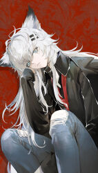  1girl absurdres animal_ears arknights black_shirt chinese_commentary collared_shirt commentary_request denim feet_out_of_frame hair_between_eyes hair_ornament hairclip highres jeans knees_up lappland_(arknights) long_hair long_sleeves looking_at_viewer loose_necktie necktie pants red_background red_necktie scar scar_across_eye scar_on_face shirt sitting solo torn_clothes torn_pants wolf_ears wolf_girl yinhepongpong 