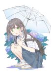  1girl bag blunt_bangs blush braid brown_hair flower french_braid green_eyes highres holding holding_umbrella long_hair looking_at_viewer maigoyaki open_mouth original school_bag shirt shoes sidelocks simple_background skirt smile solo squatting transparent transparent_umbrella umbrella white_background 