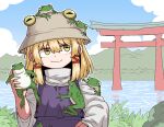  1girl animal blonde_hair brown_headwear closed_mouth day formicid frog hair_between_eyes hat long_sleeves medium_hair moriya_suwako outdoors purple_skirt purple_vest shirt skirt smile solo torii touhou upper_body vest white_shirt wide_sleeves yellow_eyes 