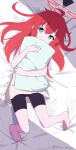  1girl ahoge barefoot bed_sheet bike_shorts blue_archive blue_eyes bright_pupils commentary_request halo highres holding holding_pillow long_hair looking_at_viewer lying maki_(blue_archive) millet_pepper on_back pillow red_halo redhead shirt solo toes twitter_username white_pupils white_shirt 