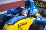  1girl animal_ears balladeluce blue_gloves blush bow car clenched_hands cosplay driving ear_bow fernando_alonso fernando_alonso_(cosplay) formula_one formula_racer gloves green_bow highres horse horse_ears horse_girl looking_up mejiro_mcqueen_(umamusume) motor_vehicle purple_hair race_vehicle racecar racing_suit real_life renault solo spoiler_(automobile) sponsor umamusume vehicle_focus violet_eyes 
