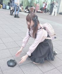  1girl backpack bag black_skirt brown_hair censored commentary cosplay_photo derivative_work explosive frilled_shirt frills highres jirai_kei kneeling korean_commentary long_sleeves mine_(weapon) original outdoors people photo_(medium) pink_shirt scribble_censor shirt skirt solo_focus 