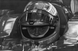  1boy car commentary english_commentary fabiodesenhando formula_one graphite_(medium) greyscale helmet highres looking_at_viewer male_focus michael_schumacher monochrome motor_vehicle motorcycle_helmet photorealistic realistic reflection signature solo straight-on traditional_media vehicle_interior 
