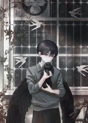  1boy absurdres animal barred_window bird black_hair black_pants black_rabbit_(animal) black_wings ca_mei closed_mouth commentary cowboy_shot grey_eyes grey_shirt hair_between_eyes highres holding holding_animal holding_rabbit long_sleeves looking_at_viewer mole_beside_mouth original outdoors pants rabbit shirt short_hair solo untranslatable_commentary white_bird window wings 