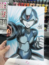  1boy arm_cannon armor art_tools_in_frame artist's_hand_in_frame blue_armor blue_helmet blue_outline clenched_hand clenched_teeth commentary english_commentary green_eyes helmet highres male_focus marker_(medium) mega_man_(character) mega_man_(series) outline photo_(medium) power_armor signature solo stanley_lau teeth traditional_media weapon 