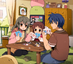  1boy 2girls bendedede brown_dress brown_eyes brown_shirt card clannad commentary dango_daikazoku drawer dress english_commentary furukawa_nagisa highres ibuki_fuuko joker_(playing_card) king_(playing_card) king_of_clubs kirby kirby_(series) long_hair multiple_girls okazaki_tomoya okazaki_ushio old_maid pink_sweater playing_card playing_games queen_(playing_card) queen_of_hearts_(playing_card) railing shirt short_hair starfish stuffed_toy sweater table television 
