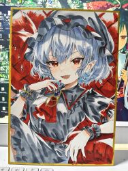  1girl absurdres alternate_color ascot bat_wings black_hat black_shirt black_skirt black_wrist_cuffs blue_hair brooch chinese_commentary collared_shirt commentary_request fang frilled_shirt_collar frills hat hat_ribbon highres jewelry l0e9s29p looking_at_viewer mob_cap open_mouth photo_(medium) pointy_ears puffy_short_sleeves puffy_sleeves red_ascot red_eyes red_nails remilia_scarlet remilia_scarlet_(tiny_devil_mistress) ribbon shikishi shirt short_hair short_sleeves sitting skin_fang skirt skirt_set smile solo touhou touhou_lostword traditional_media wings wrist_cuffs 